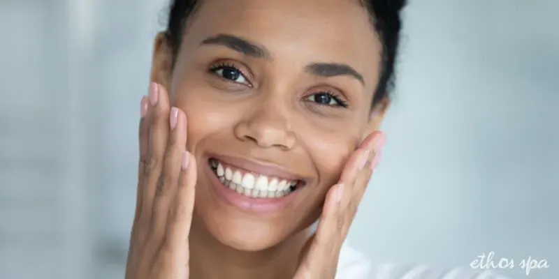 Smiling woman touching her smooth, clear cheeks