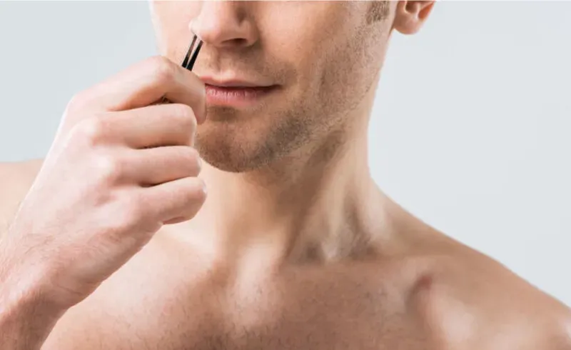 hansom man plucking his nose hair