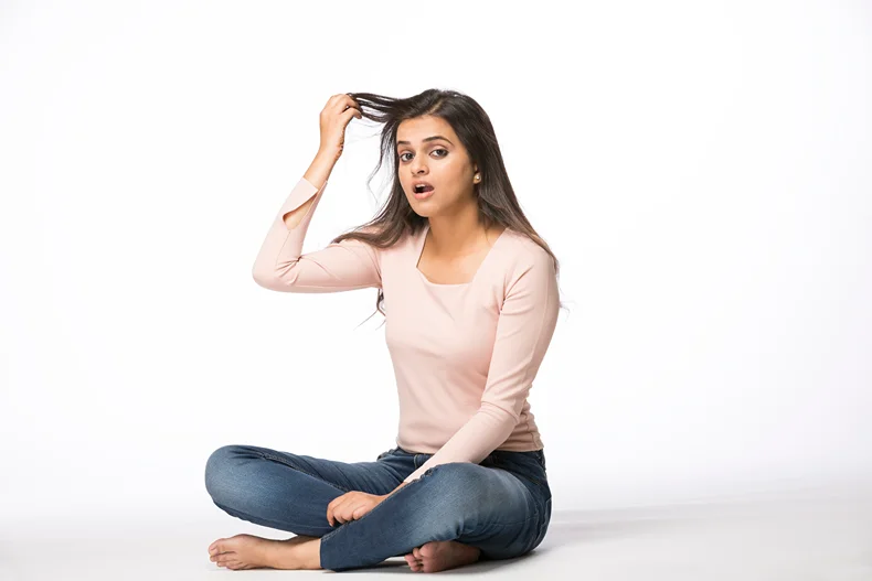 A woman with hair loss problem holding strands of her hair up.
