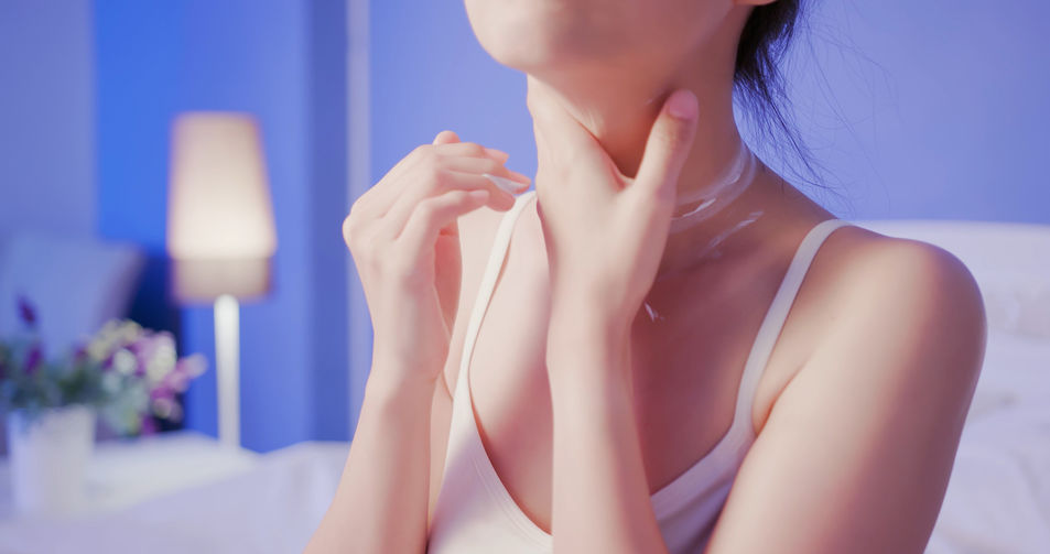 Woman applying cream to her neck