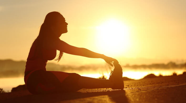 woman stretching during sunset